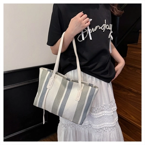Detailed view of large striped canvas tote bag in blue and white on model shoulder