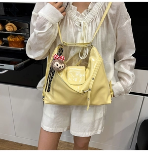 Detail of yellow patent leather tote with adjustable strap and plush bear charm