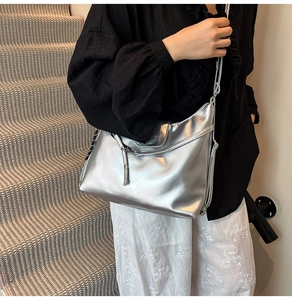 Close-up of metallic silver tote bag showing mirror texture and flap closure detail