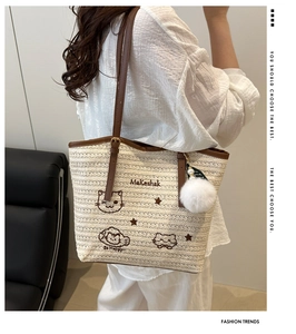 Détail du sac cabas en paille avec broderie chat et bandoulière en cuir marron élégante