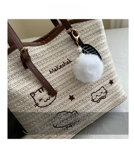 Détail d'un sac cabas tissé avec broderie chat marron et pendentif perle peluche