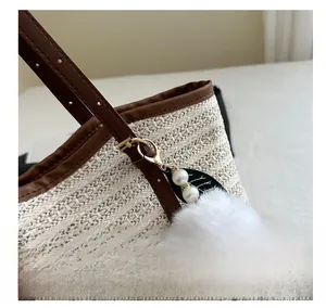Détail d'un sac cabas tissé avec poignée en cuir marron et breloque en fourrure