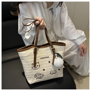 Détail du sac cabas en paille avec broderie chat et anses en cuir porté par un mannequin