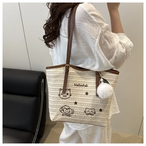 Détail du sac cabas en paille tissée avec anses en cuir marron et broderie chat