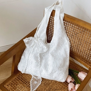 Elegant white lace tote bag with floral embroidery and large bow on vintage chair