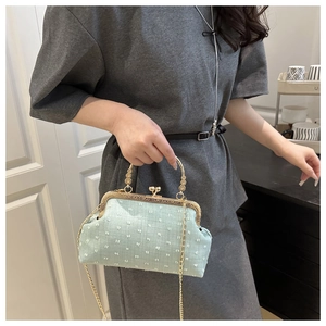 Detail of mint green vintage shell handbag featuring textured fabric and metal clasp