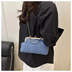 Sac bandoulière en denim bleu avec poignée dorée et chaîne porté par un mannequin
