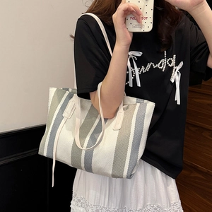 Vertical striped canvas tote bag with leather straps worn by model for office commute