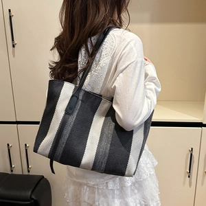 Large capacity black and white vertical striped canvas tote bag worn by a model