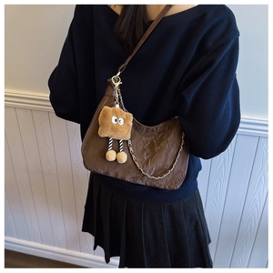 Detail view of brown pleated crescent bag with metal chain and plush bread pendant
