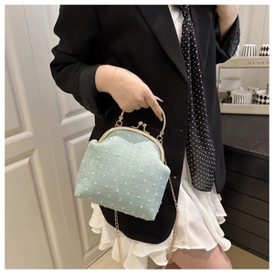 Macro view of mint green kiss-lock bag with white polka dot texture and gold handle