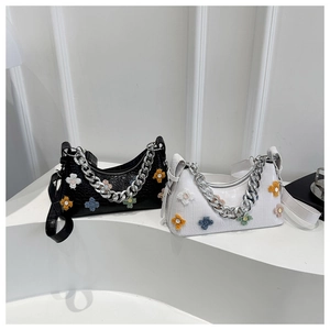 Detail of crocodile pattern underarm bag with plush flower appliques and silver chain