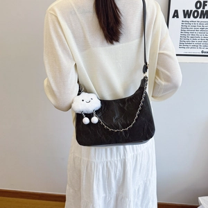Minimalist black leather tote bag with gold chain and plush cloud charm on female model