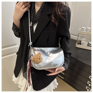 Sac bandoulière argenté métallisé avec pendentif ours porté avec blazer noir