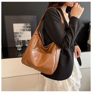 Detailed view of brown PU leather tote bag featuring front pocket and embossed fashion logo