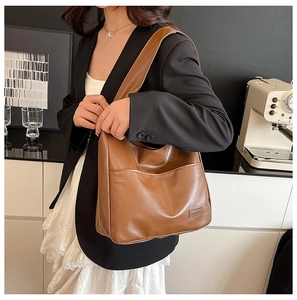 Detail of soft brown PU leather tote bag with a front pocket and textile brand label