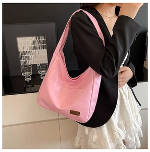 Detail of pink PU leather tote bag with fashion label showing soft texture and large capacity