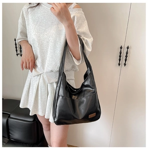 Detail of minimalist black PU leather hobo bag showing soft texture and wide shoulder strap