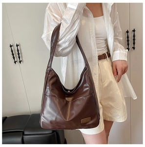 Detail of vintage brown tote bag showing smooth leather texture and fashion brand tag