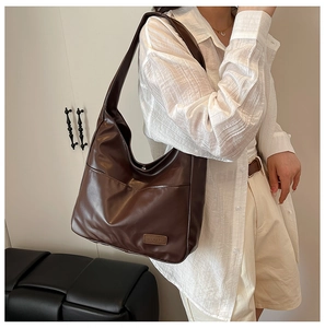 Detail of a brown PU leather hobo bag featuring a fashion tag and spacious side pocket