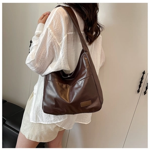 Close-up of soft brown PU leather shoulder bag with exterior pocket and brand detail