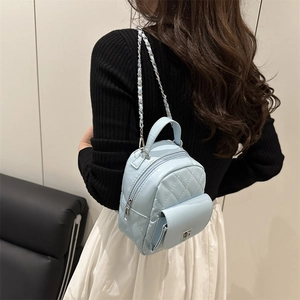 Hellblaue Mini-Rucksack mit Rautensteppung und Silberkette, getragen von einem Modell