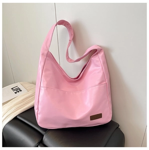 Close-up of pink oversized PU tote bag featuring front pocket and brown logo label