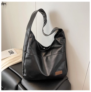 Close-up of black PU leather tote bag featuring a minimalist fashion label and front pocket