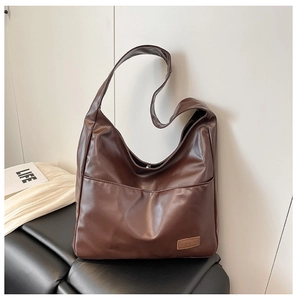 Close-up of deep brown soft PU leather tote bag featuring a front pocket and logo detail