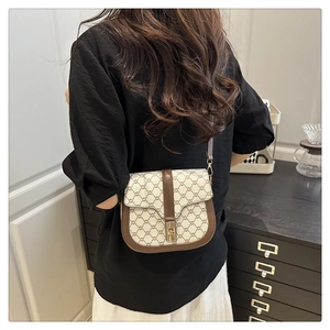 Detail view of stylish saddle bag with golden metal rotating buckle and wide shoulder strap