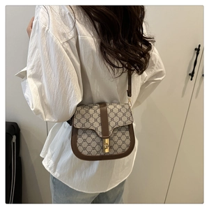 Close-up of brown vintage saddle bag featuring golden square lock and leather edge detail
