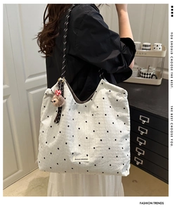 Detail of cream quilted tote bag with floral embroidery and cute plush animal charm