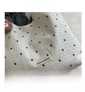 Close-up of pleated white tote bag featuring black floral print and AGOGO woven label