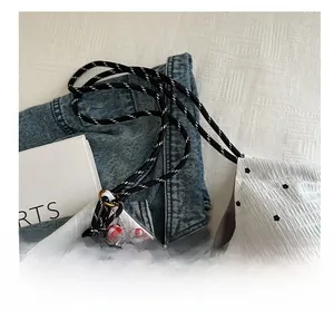 Close-up of white floral mesh tote with braided handles and a small bear pendant