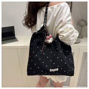 Detailed texture of black polka dot corduroy tote with shelliemay plush charm and rope strap