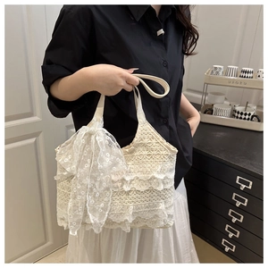 Gros plan sur le sac fourre-tout en dentelle blanc cassé avec grand nœud et texture