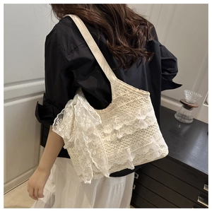 Detailed view of white lace hobo bag with tiered embroidery and large side ribbon bow