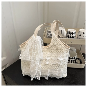 Detail of white layered lace tote bag featuring decorative lace bow and leather handle