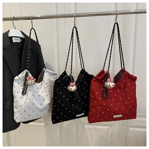 Detail of floral tote bags with woven handles and plush bear charms on hooks