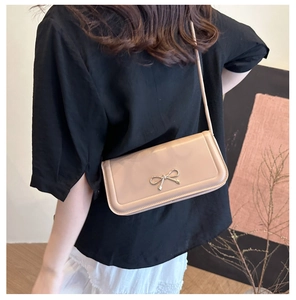 Détail d'un sac bandoulière beige élégant avec une boucle métallique en forme de nœud