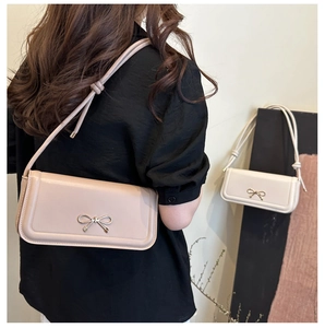 Détail du sac baguette élégant avec un nœud métallique et une bandoulière nouée fine