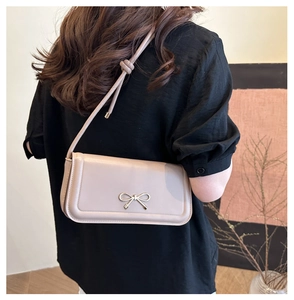 Détail du sac bandoulière beige avec boucle nœud en métal et bandoulière nouée
