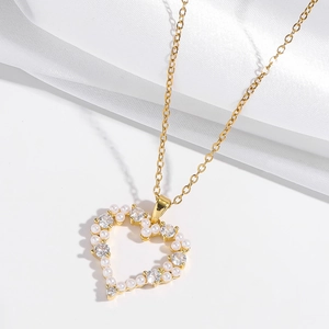 Détail du pendentif cœur ajouré avec perles et cristaux sur une chaîne dorée