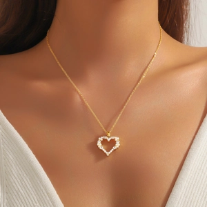 Élégant collier pendentif cœur doré avec perles et cristaux porté sur un cou féminin