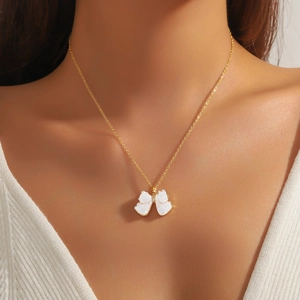 Elegant gold-tone butterfly pendant necklace with white textured zircon worn by model