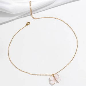 Gold butterfly necklace with pink zircon wings on elegant white silk backdrop