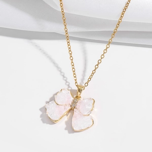 Detailed macro of a gold butterfly pendant with pink crystal and zircon on white silk