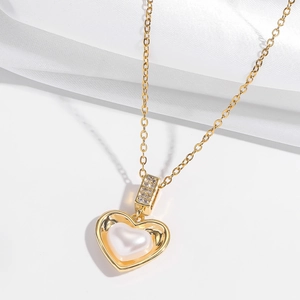 Detail of gold heart pendant with pearl inlay and shimmering zircon accents on silk