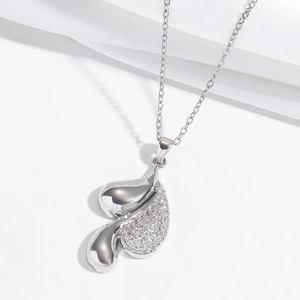 Macro shot of silver teardrop pendant with micro-pave white zircons on white silk