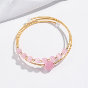Detail of gold multi-layer wrap bracelet featuring pink beads in a mouse-shaped design